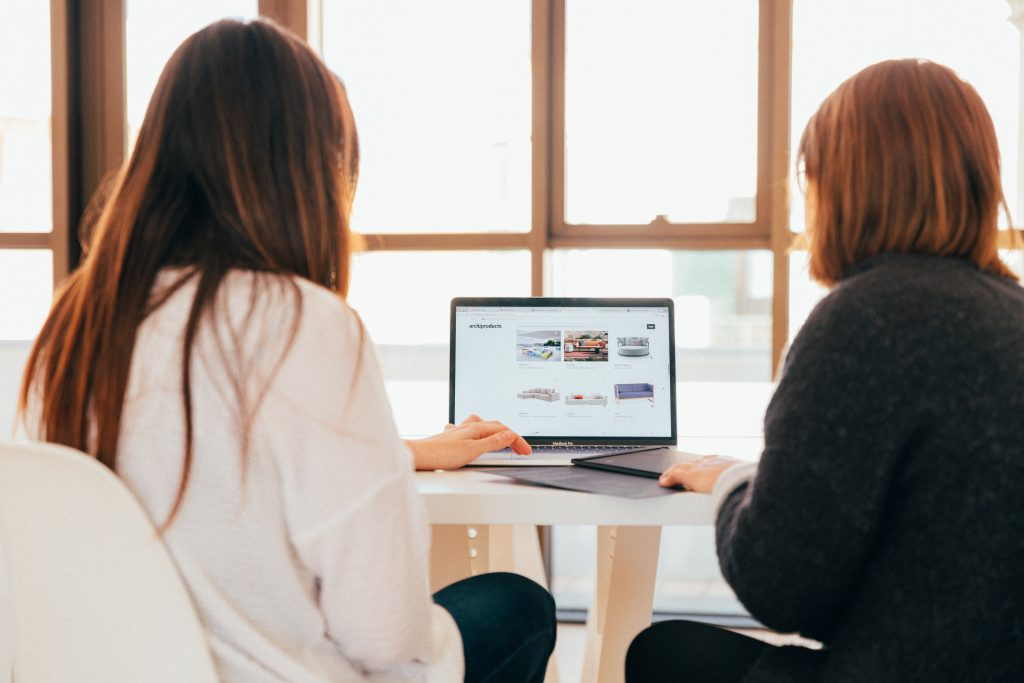 Two people sat at table, looking at laptop