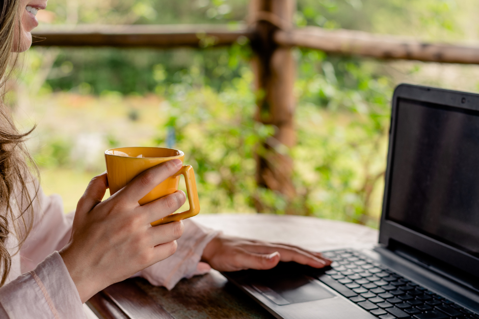 woman doing work on laptop with a coffee